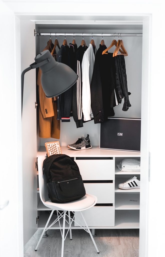 dressing avec vêtements suspendus chaussures et un sac à dos posé sur une chaise