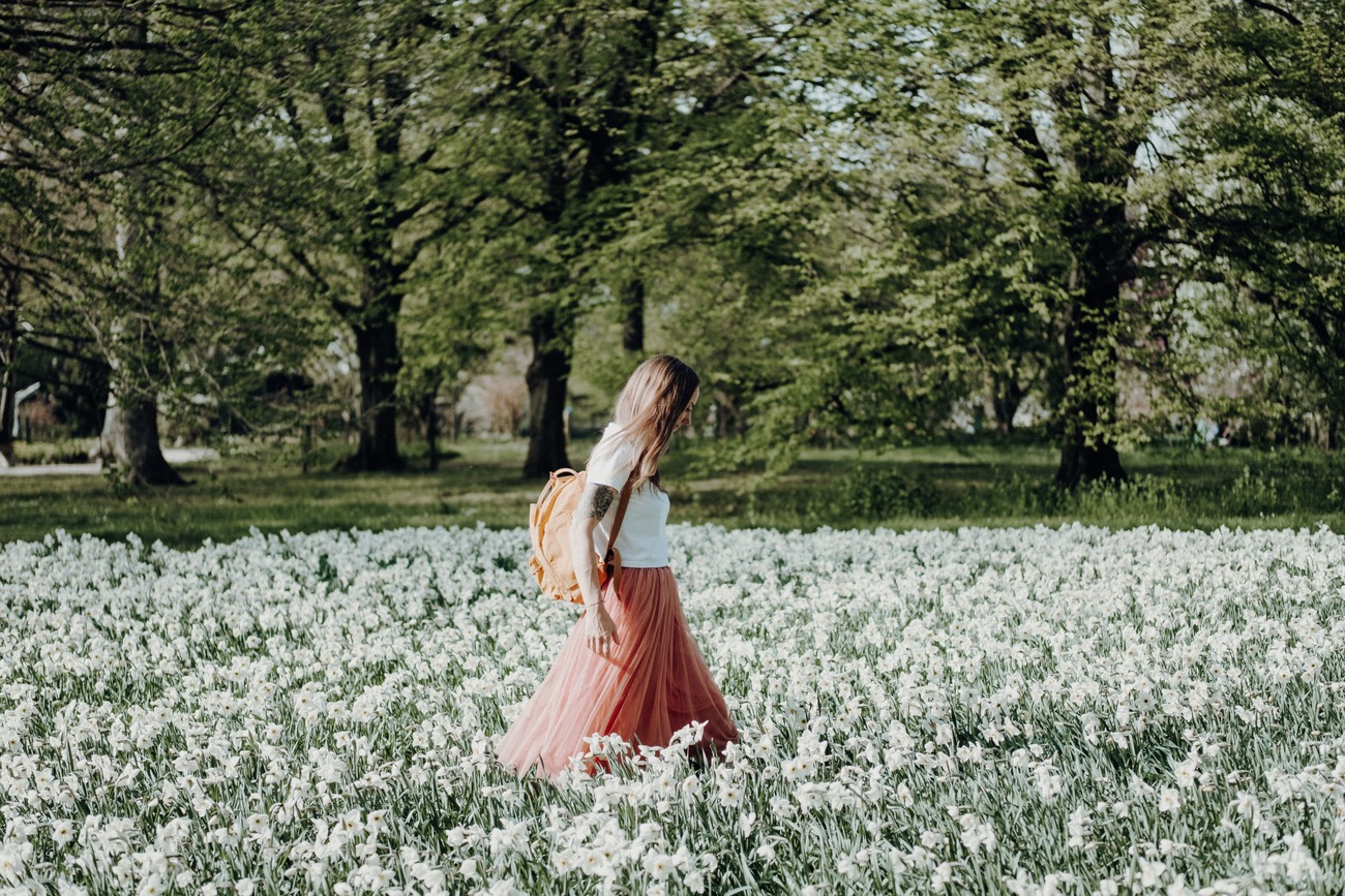 femme au look bohème qui marche dans les fleurs